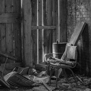 Weathered chair beside a metal barrel in an abandoned room