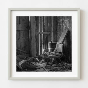Black and white photograph of an abandoned chair in a ruined interior