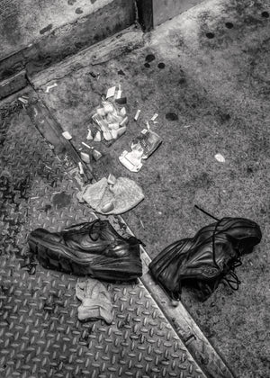 Two discarded shoes and street debris on Manhattan pavement