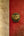 Weathered gold face knocker with iron ring on cracked red paint