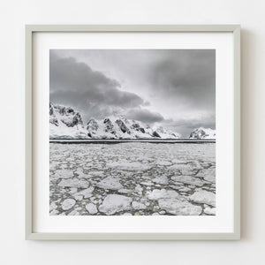 Broken Antarctic sea ice beneath snow-covered mountains