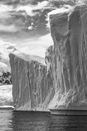 Towering sculpted iceberg wall in Antarctica beneath cloudy skies