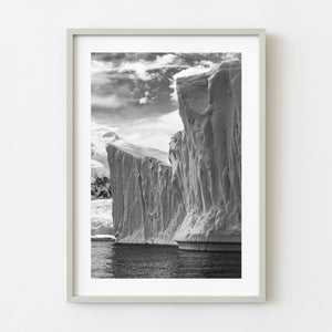 Black and white Antarctica iceberg cliffs rising above dark water