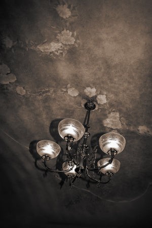 Ornate chandelier beneath floral ceiling in Barcelona