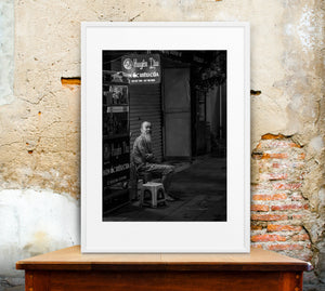 Black and white Hanoi street photography with seated elderly man