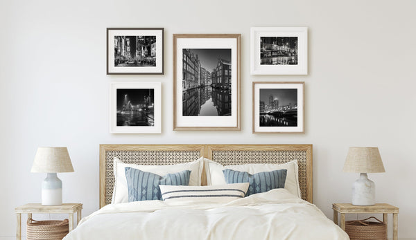 Collection of framed black and white photographs styled above a bed
