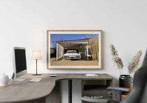 Old Chevrolet parked beneath a peeling white wooden carport