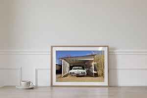 White Chevrolet framed by aged woodwork under a clear blue sky