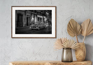 Classic Cuban automobile on wet pavement beneath streetlights