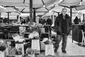 Croatian market vendor standing beside bouquets of flowers