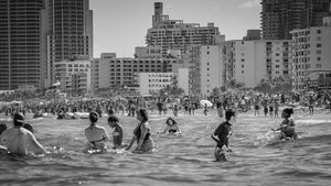 Black and white photograph of beachgoers wading in the surf at South Beach