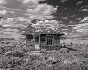 Weathered ghost town structure beneath a cloud-filled Nevada sky