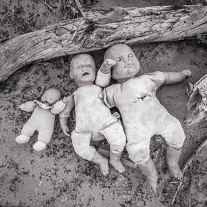 Black and white photograph of abandoned weathered dolls