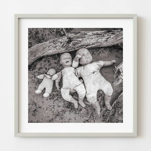 Three discarded dolls lying in sand in the American Southwest