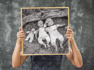Overhead view of discarded dolls on sandy ground