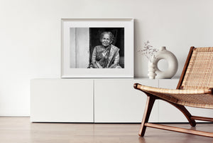 Older Indian woman seated in a dark doorway wearing a saree