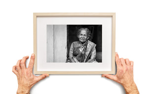 Elderly woman in traditional Indian saree beside a pale wall