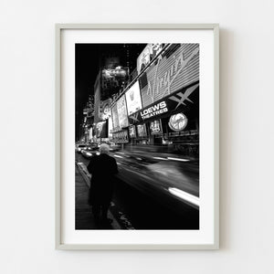 Elderly woman beside moving traffic in Times Square at night