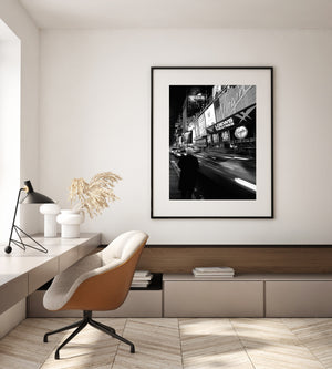 Woman standing beside blurred cars and illuminated New York signs
