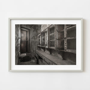 Black-and-white Ellis Island Hospital stock room with peeling cabinets
