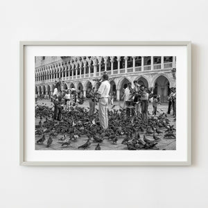 Tourists feeding pigeons in Piazza San Marco Venice in black and white