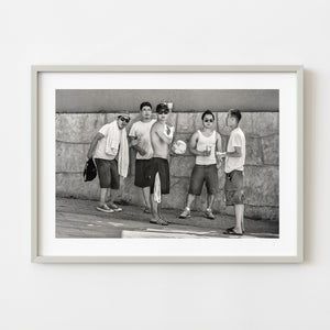 Five men standing against a stone wall in black and white