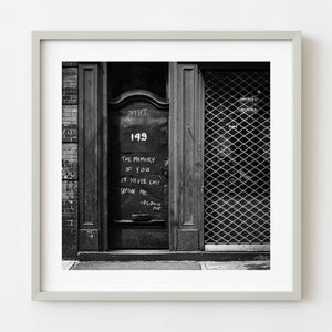 Black and white photograph of a weathered Manhattan door with a handwritten memory message