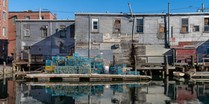 Weathered gray fish market with lobster traps along a Maine dock