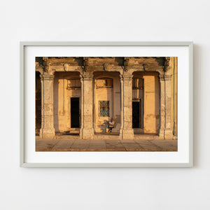 Man reading newspaper beneath columns in Havana Cuba