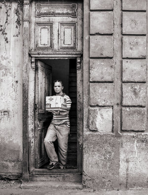 Black and white Havana street photograph of man standing in aged doorway