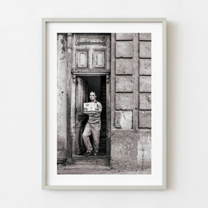Man carrying a box through a weathered Havana doorway in black and white