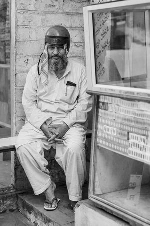 Bearded man seated beside a street display case in India