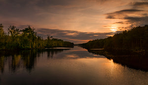 Warm orange sky reflected across calm water