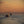 Golden evening light over cargo ships, blue-grey water and a mountain horizon in Japan.