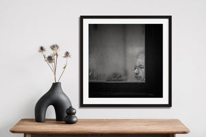 Square black and white image of a face behind textured glass