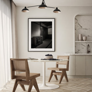 Light catches the fittings of a dark Japanese storage chest against a plain wall.