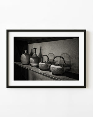 Patterned iron kettles and ceramic bottles on a shelf at Matsue's Samurai Residence, Japan, in black and white.