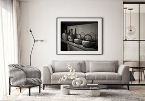 Light catches raised designs on iron vessels arranged along an old wooden shelf.