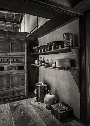 Ceramic bottles, handled vessels and a wooden cabinet in a historic Japanese kitchen interior.