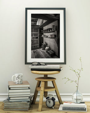 Rounded pots and curved handles contrast with straight wooden shelves in Matsue's historic house.