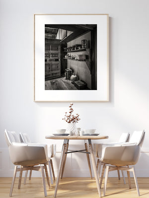 Quiet Japanese kitchen interior with pottery, dark shelves and patterned wooden floorboards.