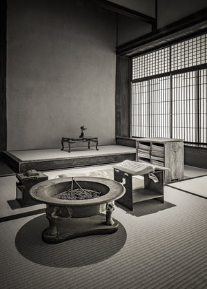 Black and white Japanese interior with a hibachi, low reading stand and tall shoji screens.