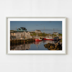 Red fishing boats in Peggys Cove harbor at sunrise