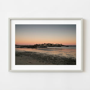 Maine coastal village at sunset beside a rocky shoreline