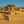 Golden limestone pillars and rippled desert sand beneath a clear blue sky