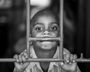 Indian boy looking through metal train window bars