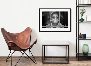 Hands gripping metal bars beneath a black and white portrait
