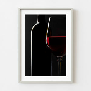 Red wine glass and bottle against a black background
