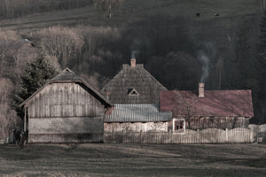 Rural wooden farmstead with smoke rising from chimneys in Romania