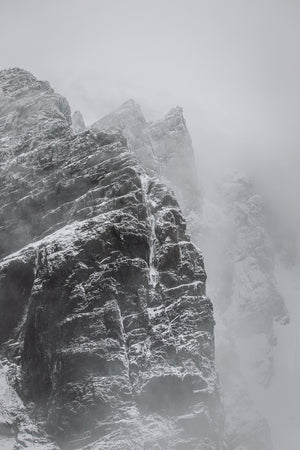 Snow lined dark rock cliffs beneath a pale Antarctic sky